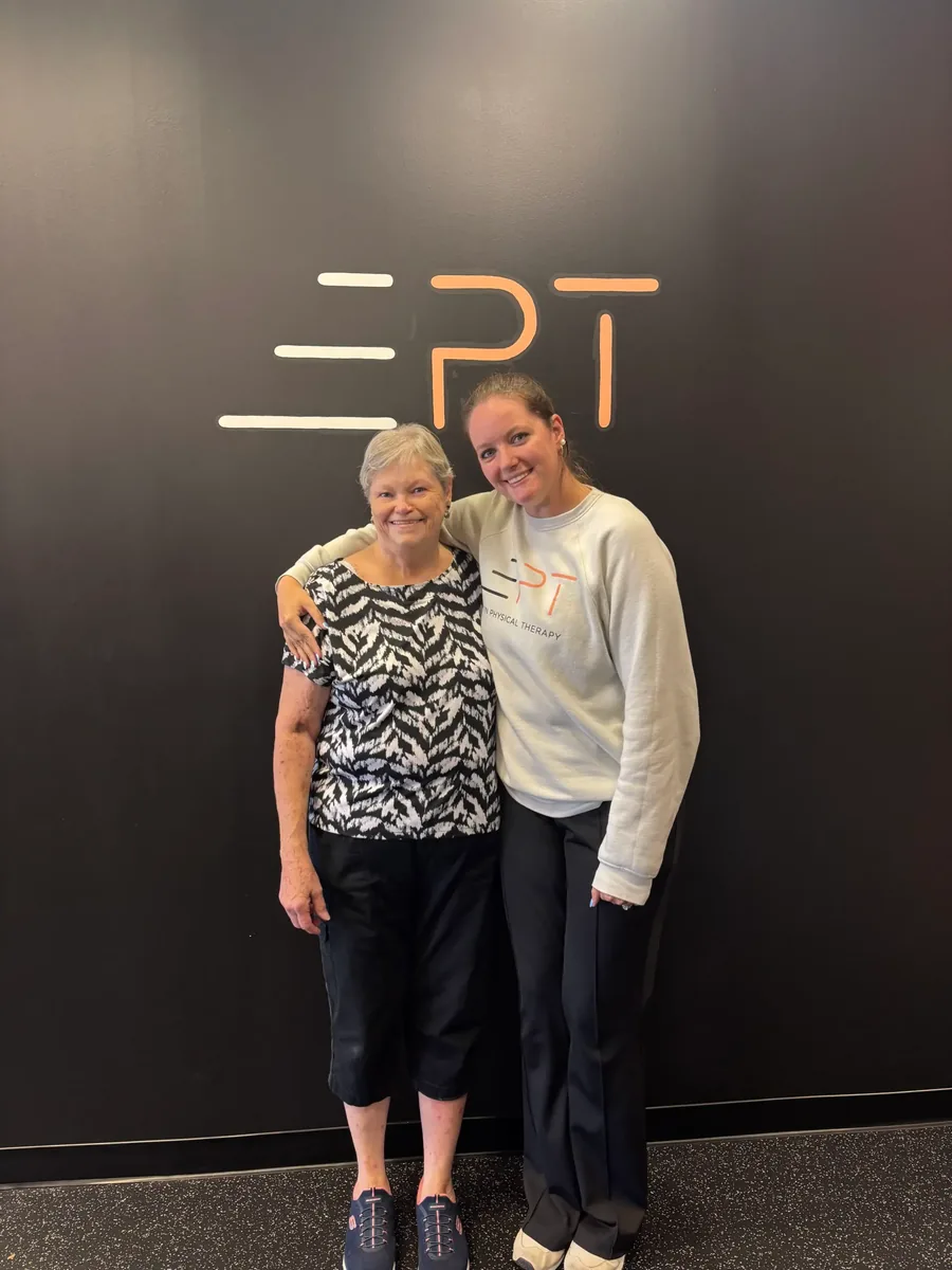 Patient and therapist posing in front of the EPT logo wall