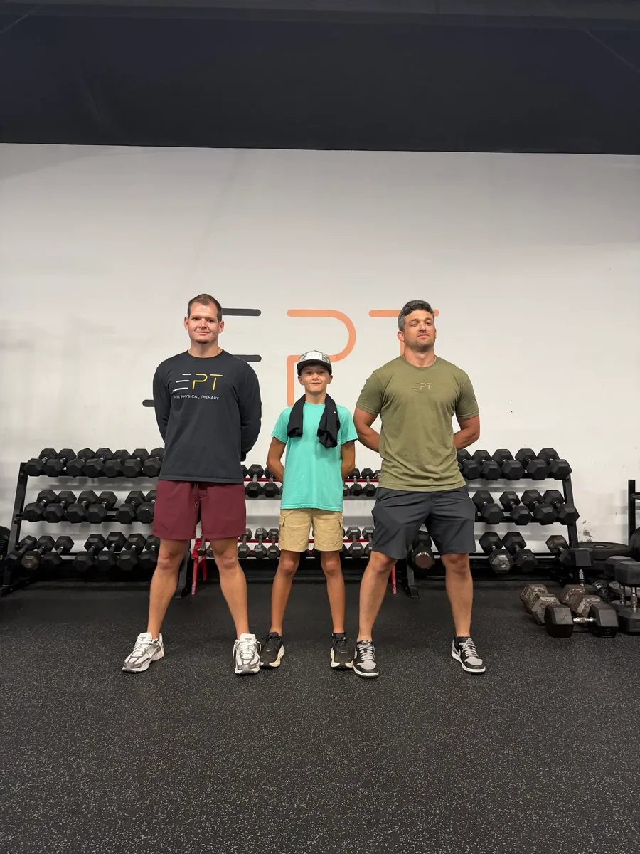 Young patient standing between two EPT therapists in the clinic gym