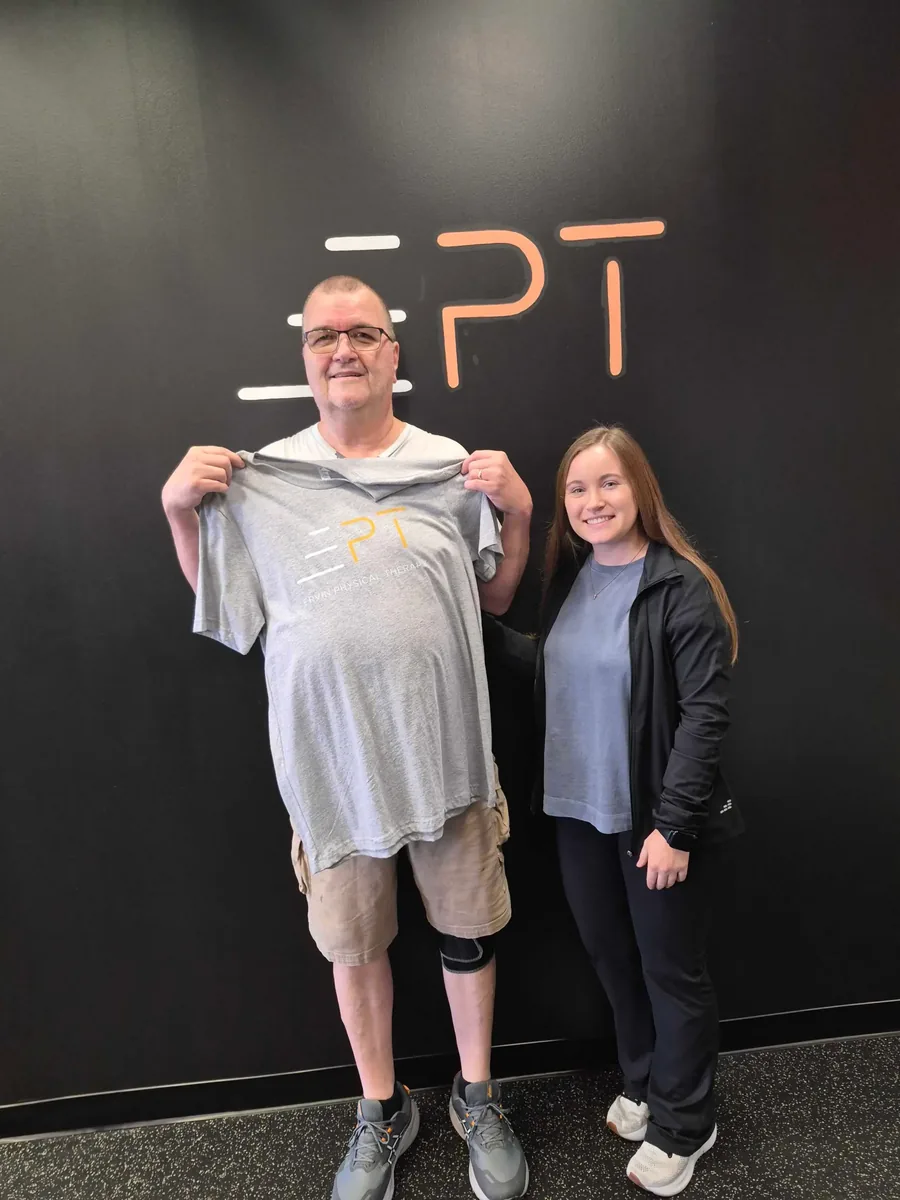 Patient holding a grey EPT shirt beside their therapist
