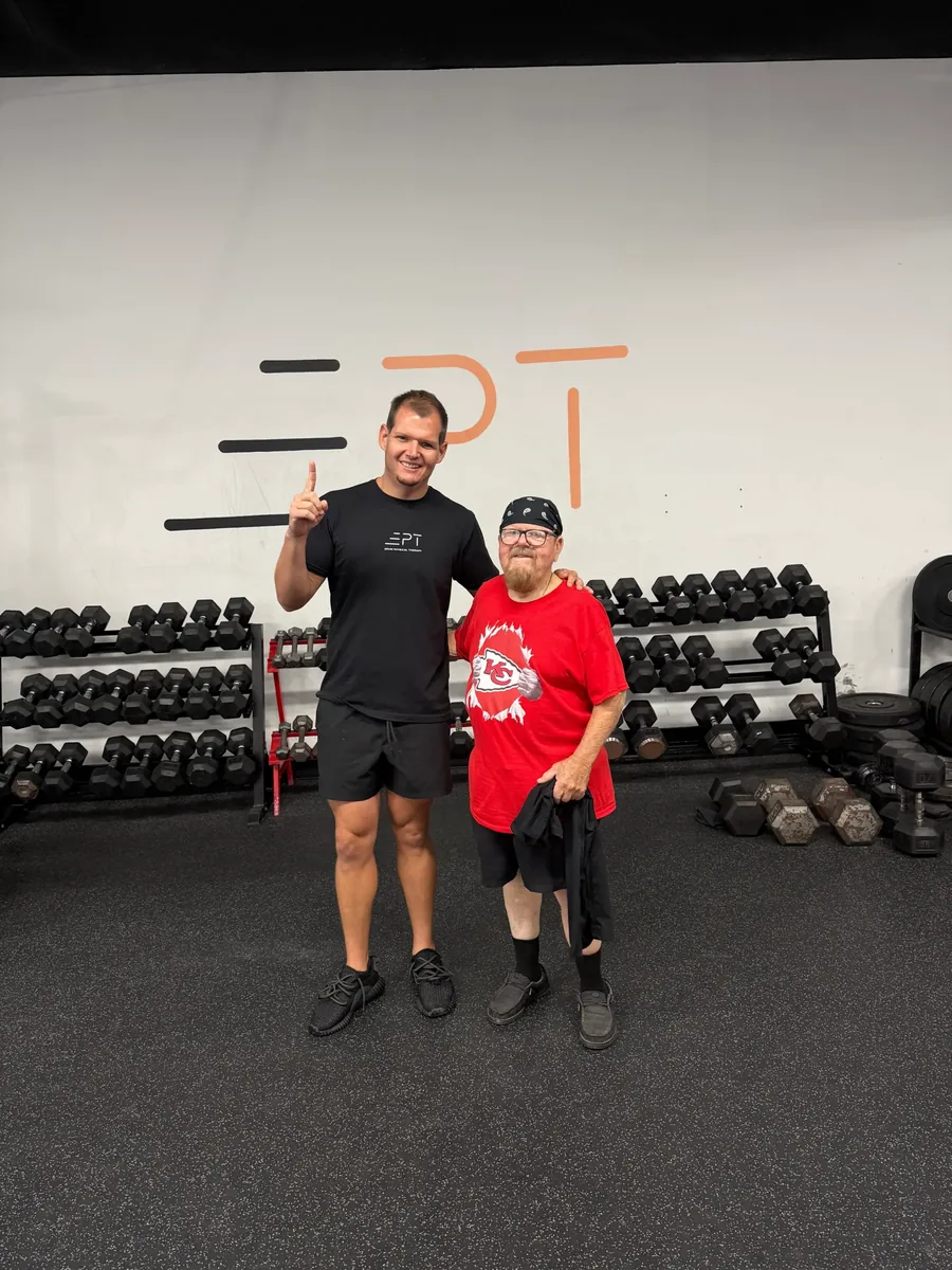 Young patient in a red shirt with their therapist in the clinic gym
