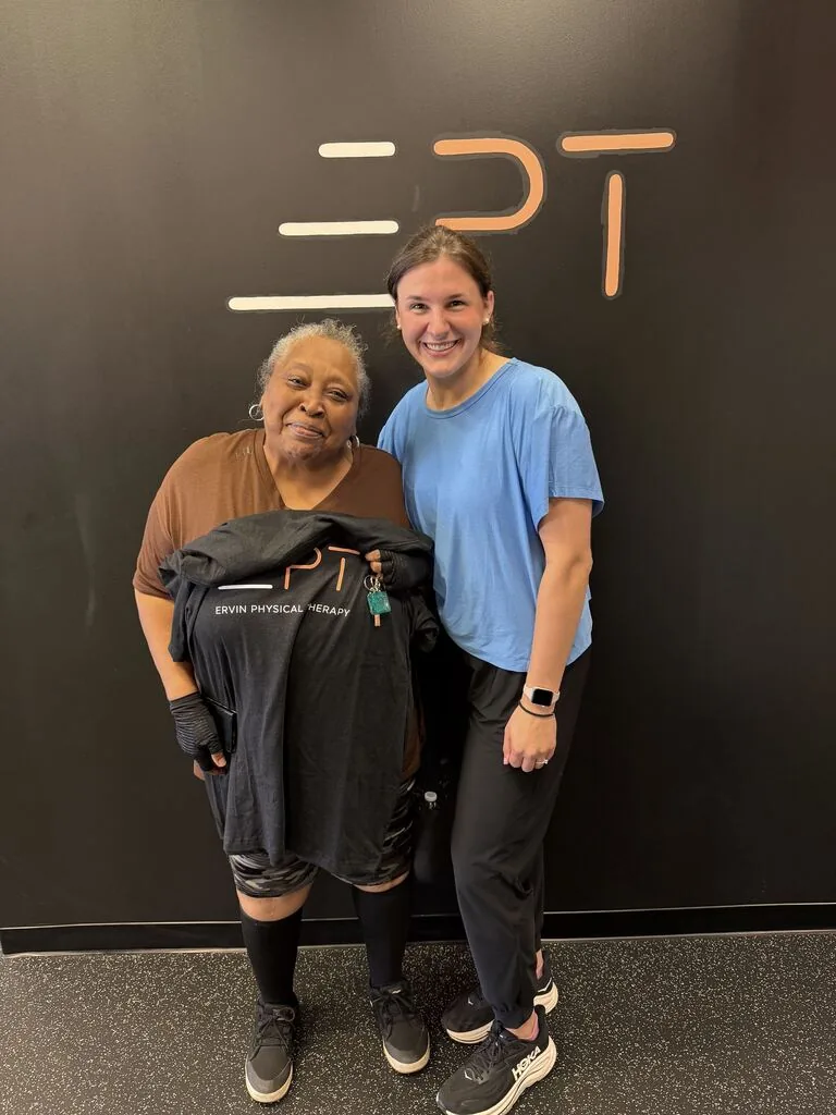 Patient holding a black EPT shirt beside their therapist