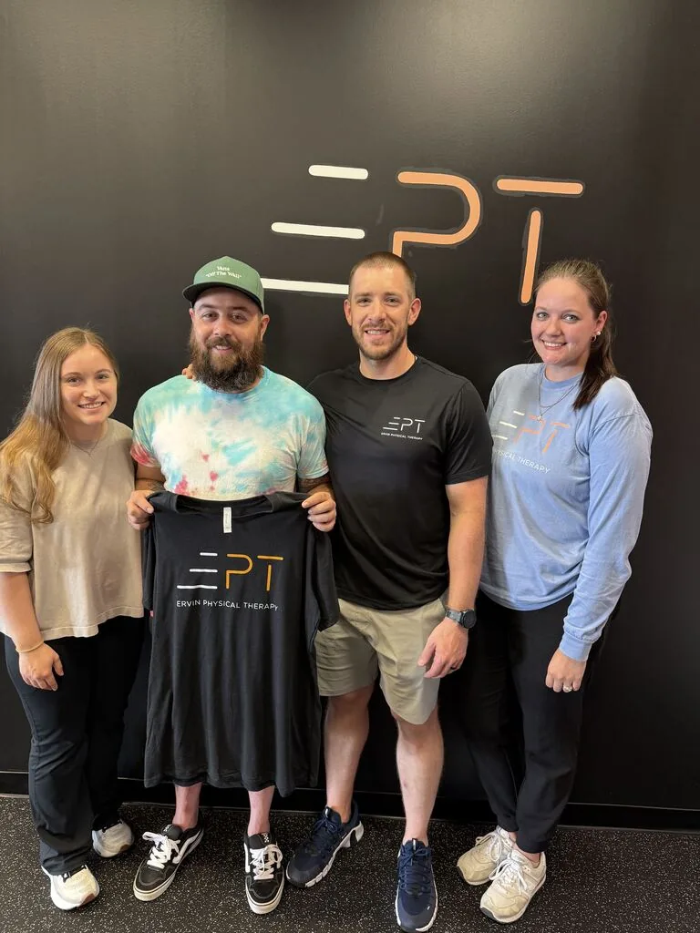 Patient holding a black EPT shirt with three members of the EPT team